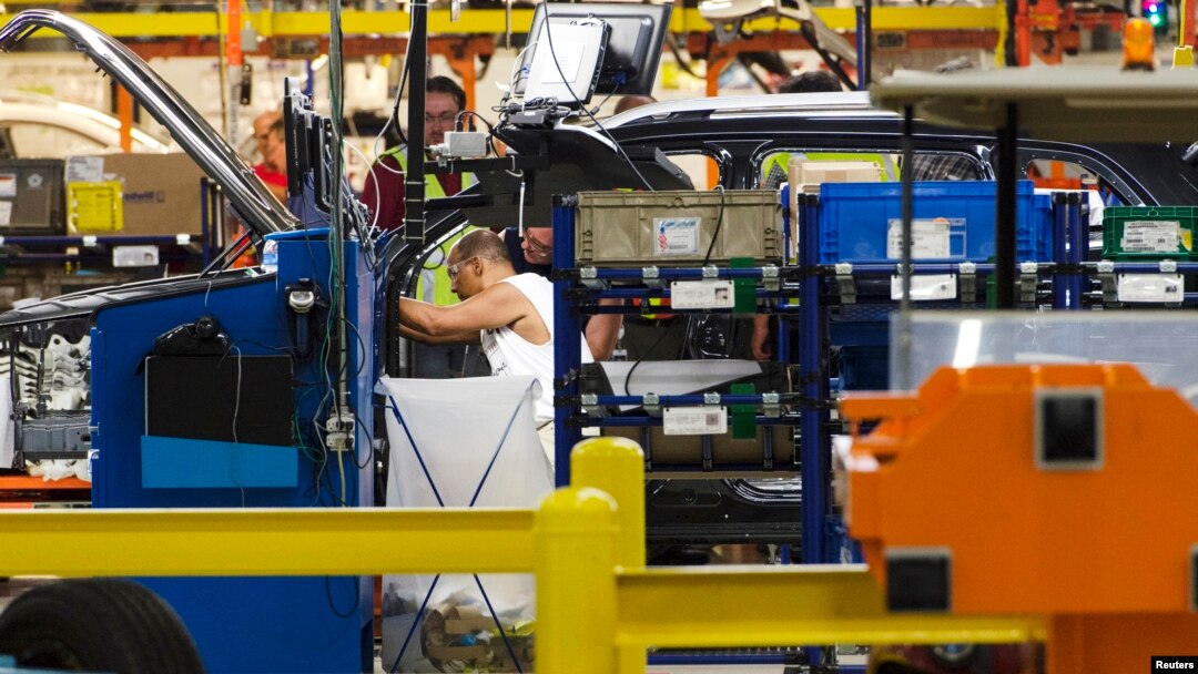 FILE - Production line workers fit parts to a Jeep Cherokee on the line at the upgraded North section of the Chrysler Toledo Assembly Complex, July 18, 2013.