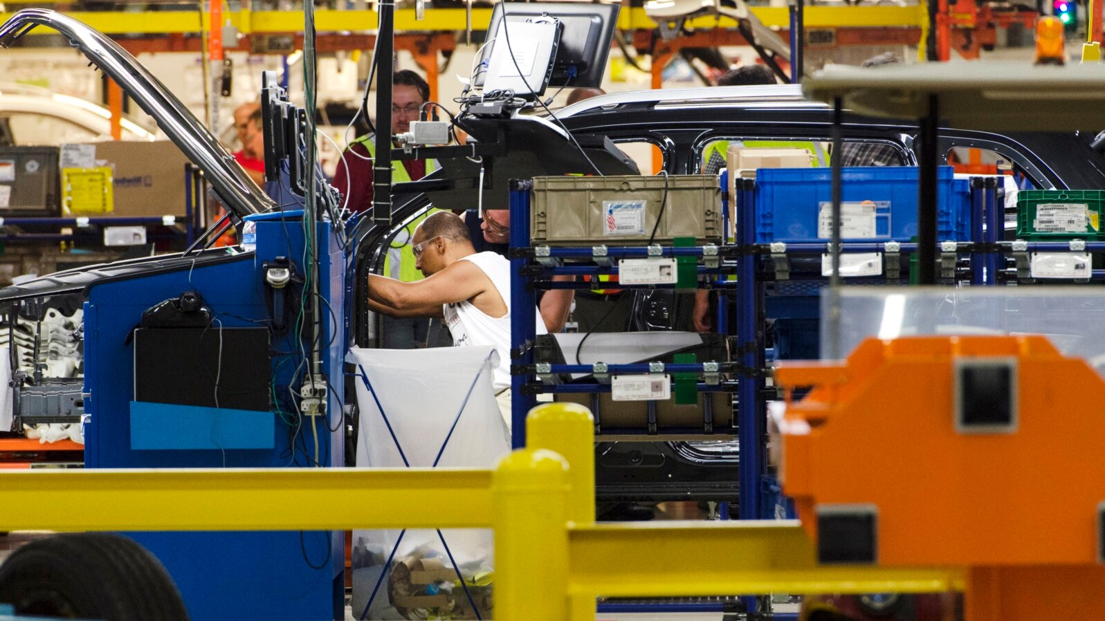 FILE - Production line workers fit parts to a Jeep Cherokee on the line at the upgraded North section of the Chrysler Toledo Assembly Complex, July 18, 2013.