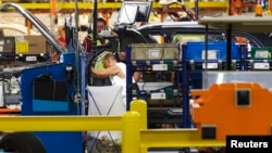 FILE - Production line workers fit parts to a Jeep Cherokee on the line at the upgraded North section of the Chrysler Toledo Assembly Complex, July 18, 2013.