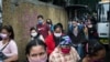 Personas con máscaras faciales en medio de la pandemia de coronavirus se agolpan en una acera cerca de una parada de autobús en Caracas, Venezuela, el lunes 1 de junio de 2020.