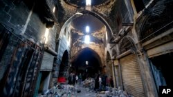 FILE - Syrians walk amid the destruction, in the Old City of Aleppo, Syria. 