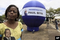 A supporter of Cameroon President Paul Biya stands next to a giant election campaign ball in Yaounde, Cameroon, October 8, 2011.