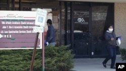 FILE - A woman leaves after checking job application information in front of IDES (Illinois Department of Employment Security) WorkNet center in Arlington Heights, Ill., April 9, 2020. 