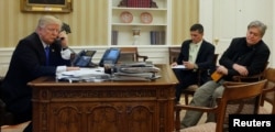 U.S. President Donald Trump, seated at his desk with National Security Advisor Michael Flynn and senior advisor Steve Bannon, right, speaks on phone in the Oval Office at the White House, Jan. 28, 2017.