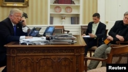 U.S. President Donald Trump, seated at his desk with National Security Advisor Michael Flynn and senior advisor Steve Bannon, right, on the phone in the Oval Office at the White House, Jan. 28, 2017. 