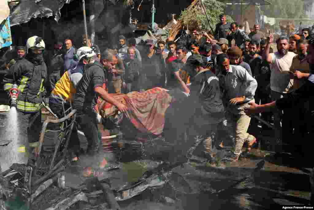 Civil defense members evacuate the body of a victim killed in a car bombing in Syria&#39;s rebel-held northern city of Afrin.