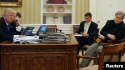 U.S. President Donald Trump, seated at his desk with National Security Advisor Michael Flynn and senior advisor Steve Bannon, right, speaks by phone with Australia's Prime Minister Malcolm Turnbull in the Oval Office at the White House, Jan. 28, 2017. 