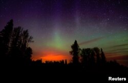 The wildfires glow underneath The Northern Lights, also known as the Aurora Borealis, near Fort McMurray, Alberta, Canada, May 7, 2016.