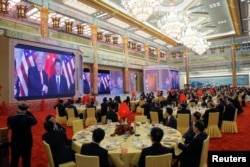 Guests watch a video about meetings between U.S. President Donald Trump and China's President Xi Jinping at a state dinner at the Great Hall of the People in Beijing, China, Nov. 9, 2017.