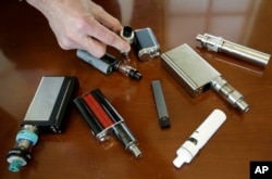 In this Tuesday, April 10, 2018 photo, vaping devices that were confiscated from students in such places as restrooms or hallways at the school in Marshfield, Mass.