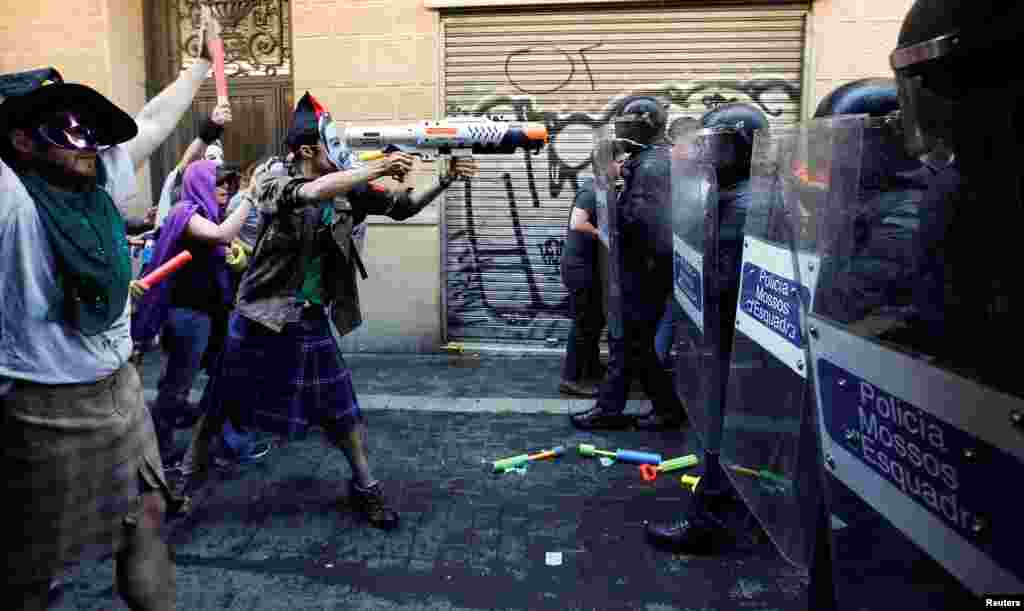 A protester squirts a water gun at Catalan regional police in full riot gear during a protest over the eviction of squatters earlier in the week from &quot;The Expropriated Bank&quot;, in Barcelona, Spain.