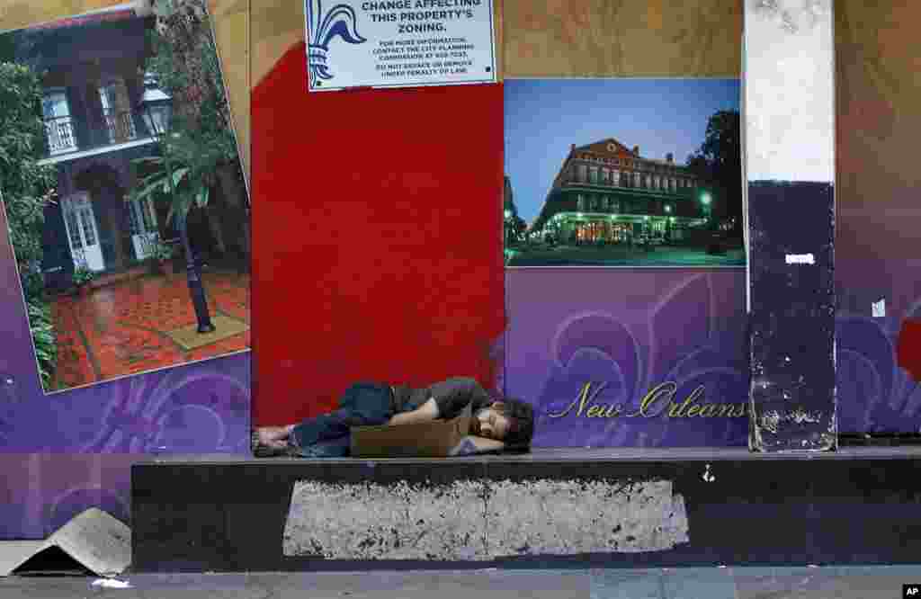A man sleeps outside a boarded up building on Canal St., prior to Tropical Storm Isaac in New Orleans, Aug. 28, 2012. 