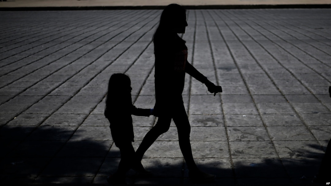 FILE - A woman and child walk during a march against human trafficking and slavery, on Paseo de la Reforma boulevard in Mexico City, Oct. 14, 2017. 