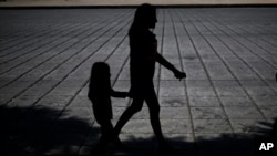 FILE - A woman and child walk during a march against human trafficking and slavery, on Paseo de la Reforma boulevard in Mexico City, Oct. 14, 2017. 