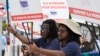 Dockworkers from Port Miami display signs at a picket line, Oct. 3, 2024, in Miami. 