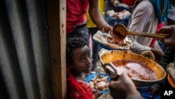 File - Elena, 7, center, lines up with other displaced Tigrayans to receive food donated by local residents at a reception center for the internally displaced in Mekele, in the Tigray region of northern Ethiopia, May 9, 2021. 