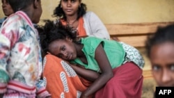Un jeune déplacé par les combats dans le nord de l'Éthiopie repose alors qu'une femme se peigne à l'école Addis Fana où ils sont temporairement hébergés, dans la ville de Dessie, en Éthiopie, le 23 août 2021.