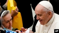 Pope Francis cheers at a newborn at the end of his weekly general audience in the Paul VI Hall at the Vatican, Dec. 1, 2021.