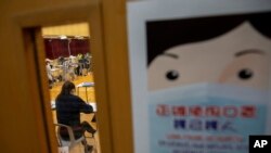 Seorang siswa yang memakai masker mengikuti ujian Diploma of Secondary Education (DSE) di sebuah sekolah di Hong Kong, Jumat, 24 April 2020. (Foto: AP)