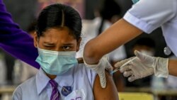 A student reacts as a health worker inoculates her with the dose of Pfizer-BioNTech vaccine against COVID-19 at a school in Colombo, Sri Lanka, Jan. 7, 2022.