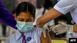 A student reacts as a health worker inoculates her with the dose of Pfizer-BioNTech vaccine against COVID-19 at a school in Colombo, Sri Lanka, Jan. 7, 2022.