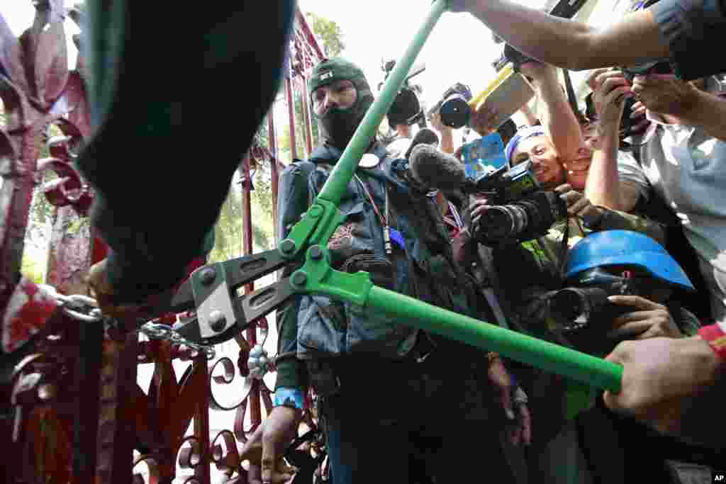 Manifestantes arrombam o portão da sede da polícia durante os protestos em Banguecoque, Jan. 22, 2014. 