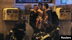 Des membres de la brigade anti-incendie française portent un homme blessé près de la salle de concert Bataclan après la fusillade mortelle à Paris, France, 13 novembre 2015. 