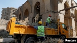 FILE - Egyptian workers wearing reflective vests are seen cleaning up an architectural landmark in old Cairo, Egypt, Oct. 16, 2018. The sale of the vests has been temporarily restricted in Egypt.