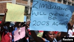 Zimbabweans hold placards during a protest against President Robert Mugabe government's handling of the economy in Harare, Zimbabwe, August 3, 2016.