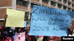 FILE: Zimbabweans hold placards during a protest against President Robert Mugabe government's handling of the economy in Harare, Zimbabwe, August 3, 2016.