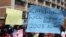 FILE: Zimbabweans hold placards during a protest against President Robert Mugabe government's handling of the economy in Harare, Zimbabwe, August 3, 2016.