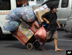FILE - A man pulls a trolley filled with used plastic bottles on a street in Bangkok, Thailand.