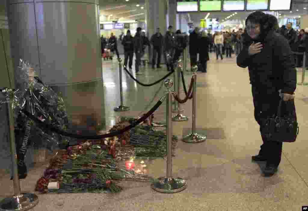 机场过路乘客纷纷放置鲜花向在24日爆炸袭击中受难死亡的人士致哀
