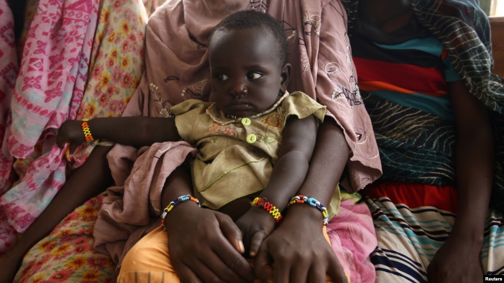 FILE - A woman holds her child as they wait to receive treatment in Kobo health center in Kobo village, one of the drought stricken areas of Oromia region, in Ethiopia, April 28, 2016. 