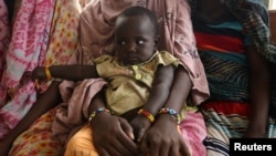 FILE - A woman holds her child as they wait to receive treatment in Kobo health center in Kobo village, one of the drought stricken areas of Oromia region, in Ethiopia, April 28, 2016. 