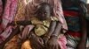 FILE - A woman holds her child as they wait to receive treatment in Kobo health center in Kobo village, one of the drought stricken areas of Oromia region, in Ethiopia, April 28, 2016. 