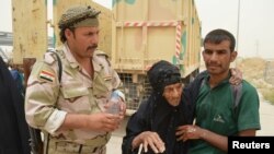 Un soldat irakien aide des civils fuyant Fallouja, Iraq, le 18 juin 2016. (REUTERS/Stringer )