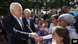 US Senators John McCain (R-AZ) (L) and Joseph Lieberman (D-CT) (2nd L) are greeted by Syrian refugee children during their visit at Yayladagi refugee camp in Hatay province on the Turkish-Syrian border, April 10, 2012.
