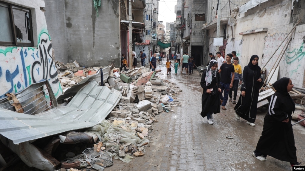 Varios palestinos caminan junto a los escombros de una casa destruida por un ataque israelí en Nuseirat, en el centro de la Franja de Gaza, el 1 de octubre de 2024.