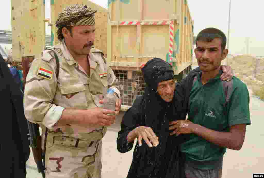 An Iraqi soldier helps civilians, who fled from Falluja because of Islamic State violence, during a dust storm on the outskirts of Falluja, Iraq, June 18, 2016.