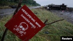 FILE - A destroyed military vehicle is seen near a landmine warning sign just outside the eastern Ukrainian town of Slaviansk, July 7, 2014. 