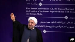 Iran's new President Hasan Rouhani waves to reporters at the conclusion of his first press conference since taking office at the presidency compound in Tehran, Aug. 6, 2013. 