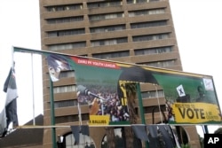 FILE - An old ripped election banner bearing a portrait of ousted President Robert Mugabe outside the headquarters of the ruling ZANU-PF building in Harare, Nov. 19, 2017.