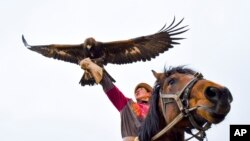 A man holding a golden eagle for an eagle hunt ride a horse during the hunting festival &quot;Salburun&quot; in Tuura-Suu, a small village nestled among the mountains, about 250 km. (156 miles) south-east of Bishkek, Kyrgyzstan.