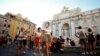 Transeúntes y turistas con máscaras junto a la Fuente de Trevi, una de las principales atracciones de Roma.