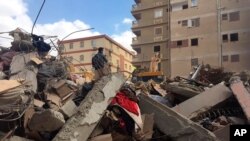 Emergency workers sift through the rubble of a collapsed apartment building in the el-Salam neighborhood, March 27, 2021, in Cairo, Egypt.