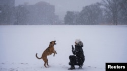 Una mujer juega con su perro en el parque Centennial de Nashville, Tennessee, en medio de una tormenta de nieve el 10 de enero de 2025.