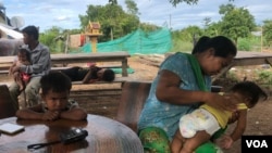 Lang Chanthoeun, 35, a villager in Kampong Thom province’s Krayea commune, looks after her daughter, who has been diagnosed with dengue fever, as she vomits while Lang Chanthoeun gives an interview to VOA, June 2019. (Sun Narin/VOA Khmer)