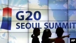 Women walk by a screen showing G20 Seoul Summit sign at the venue for the upcoming summit meeting, 02 Nov 2010