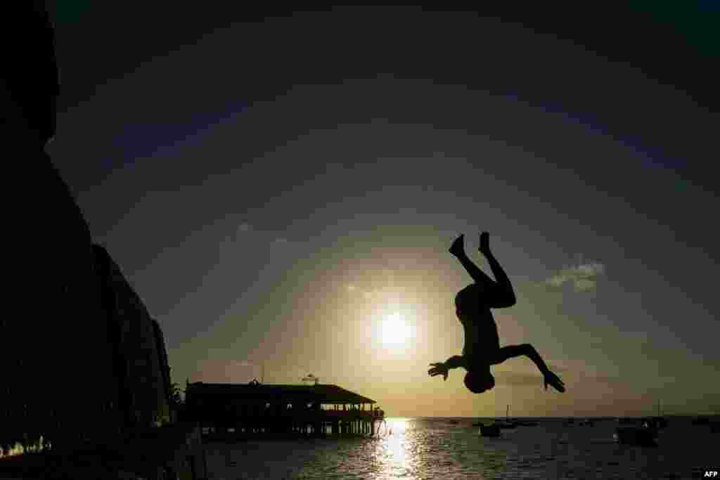 A youth jumps into the Indian Ocean at the water front of the historical Stone Town of Zanzibar, Tanzania.